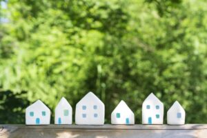 Row of small white house models with green nature background | 住宅・まちづくり・家づくり全般をイメージしたコンセプト画像