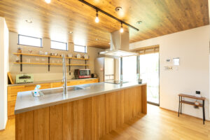 Energy-efficient modern kitchen with natural wood and stainless island counter | 省エネ住宅補助金の対象にもなる、高断熱仕様のナチュラルモダンキッチン